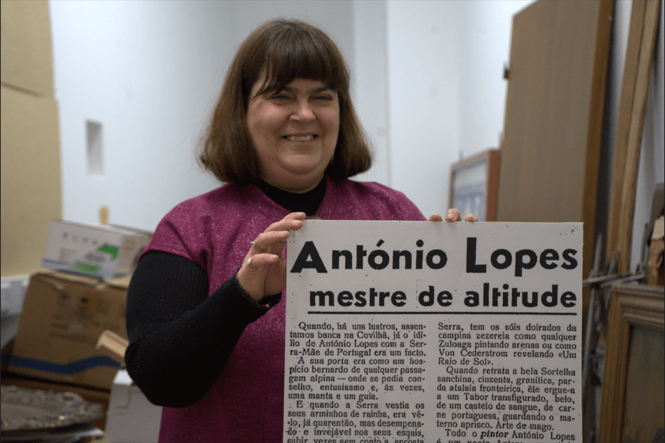 Fátima Curto segura um recorte de jornal transformado num placar. Foto da autoria de Tomás Quaresma.